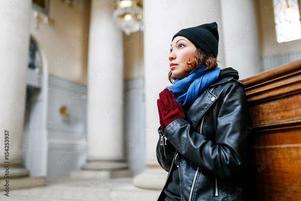 Young faithful woman praying in the church