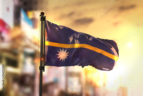 Nauru Flag Against City Blurred Background At Sunrise Backlight