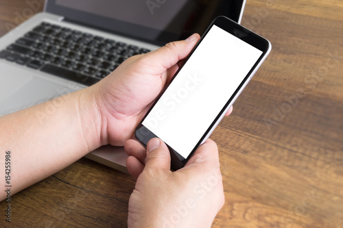 blank screen smartphone in hand with laptop blurred concept for smart life, internet of thing, IOT, digital connecting, online
