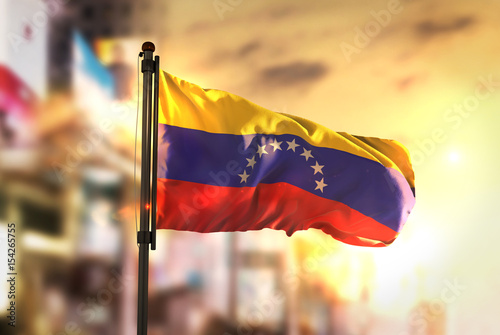 Venezuela Flag Against City Blurred Background At Sunrise Backlight photo