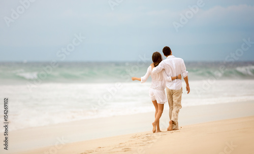 Embracing couple walking along beach