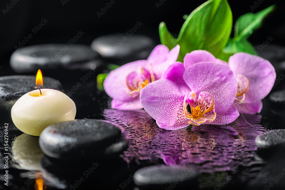 beautiful spa concept of blooming twig lilac orchid flower, green leaf, candle with water drops and zen basalt stones, close up beautiful spa concept of blooming twig lilac orchid flower, green leaf, candle with water drops and zen basalt stones, close up