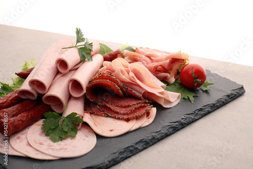 Food tray with delicious salami, pieces of sliced ham, sausage, tomatoes, salad and vegetable - Meat platter with selection