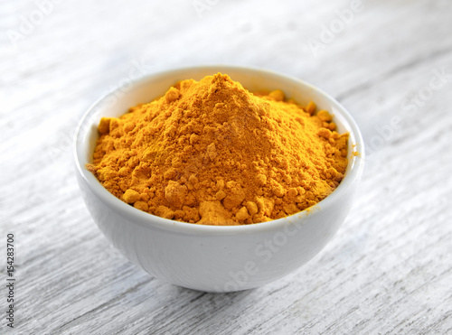 Turmeric powder in white cup on wooden floor