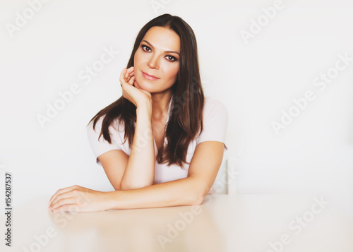 Portrait of beautiful brunette woman, arms on the table