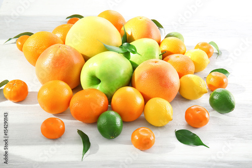 Appetizing fresh citrus fruits and apples on white wooden background