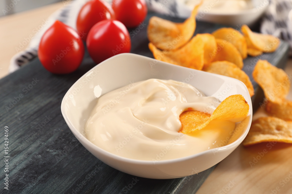 Bowl with tasty mayonnaise sauce and chips on table, closeup Bowl with tasty mayonnaise sauce and chips on table, closeup