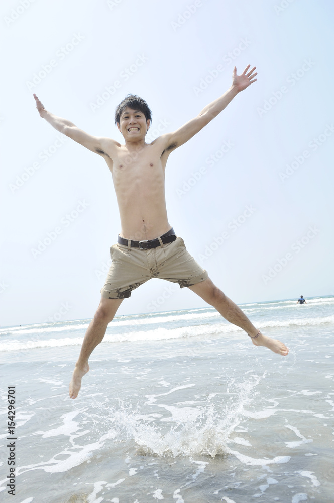 Obraz premium 海でジャンプする若い男性