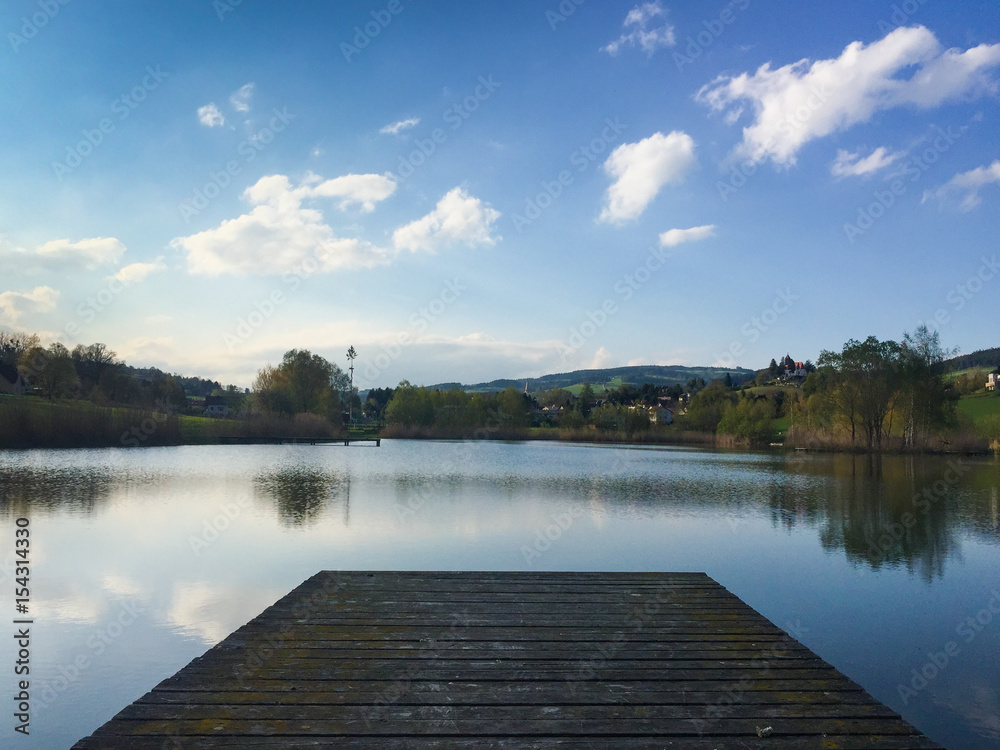 pier on a pond at sunset with blue sky and clouds
