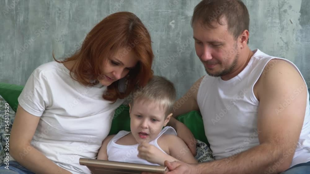 The son shows interesting in the tablet to parents. People with technology. The son shows interesting in the tablet to parents. People with technology.
