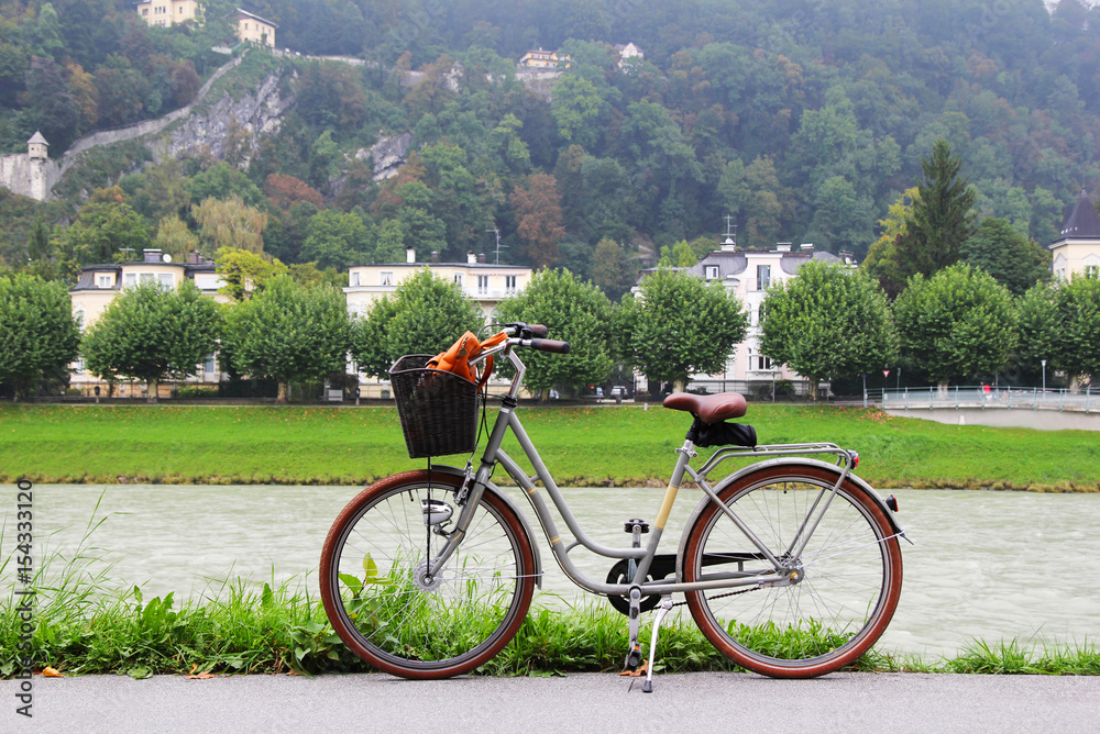 Obraz premium Travel to Salzburg, Austria. A bicycle on a view of a park, a river and mountains.