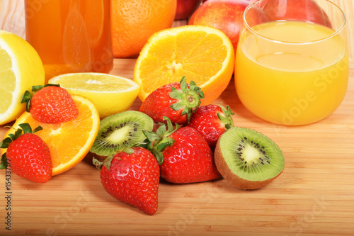 A glass of cold orange juice and strawberries