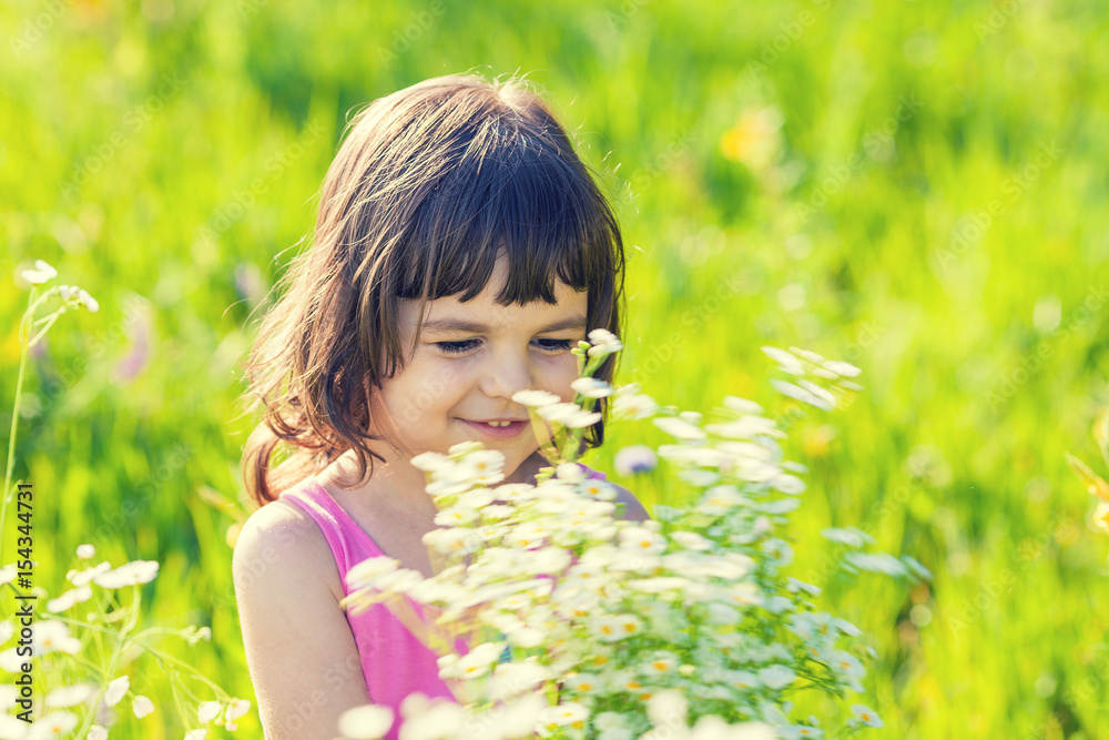 Happy little girl picking flowers in the meadow in sunny day Happy little girl picking flowers in the meadow in sunny day