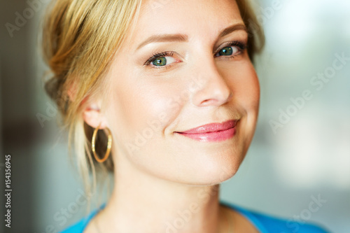 Close up portrait of beautiful blond woman with blue eyes, wearing professional makeup