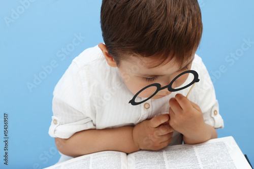 little child reading a book with fake glasses