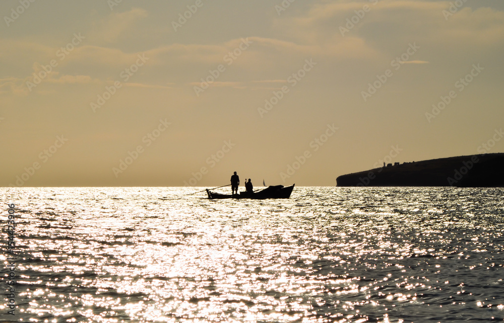 Fishing boat on the sea at sunset. Fisherman on the boat.