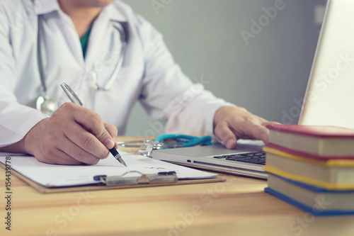 Male medicine doctor hand holding silver pen writing something on clipboard closeup. Medical care, insurance, prescription, paper work or career concept. Physician ready to examine patient and help