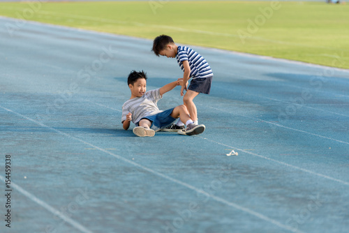 Boy help each other on blue track after fall