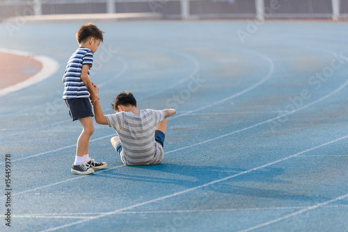Boy help each other on blue track after fall