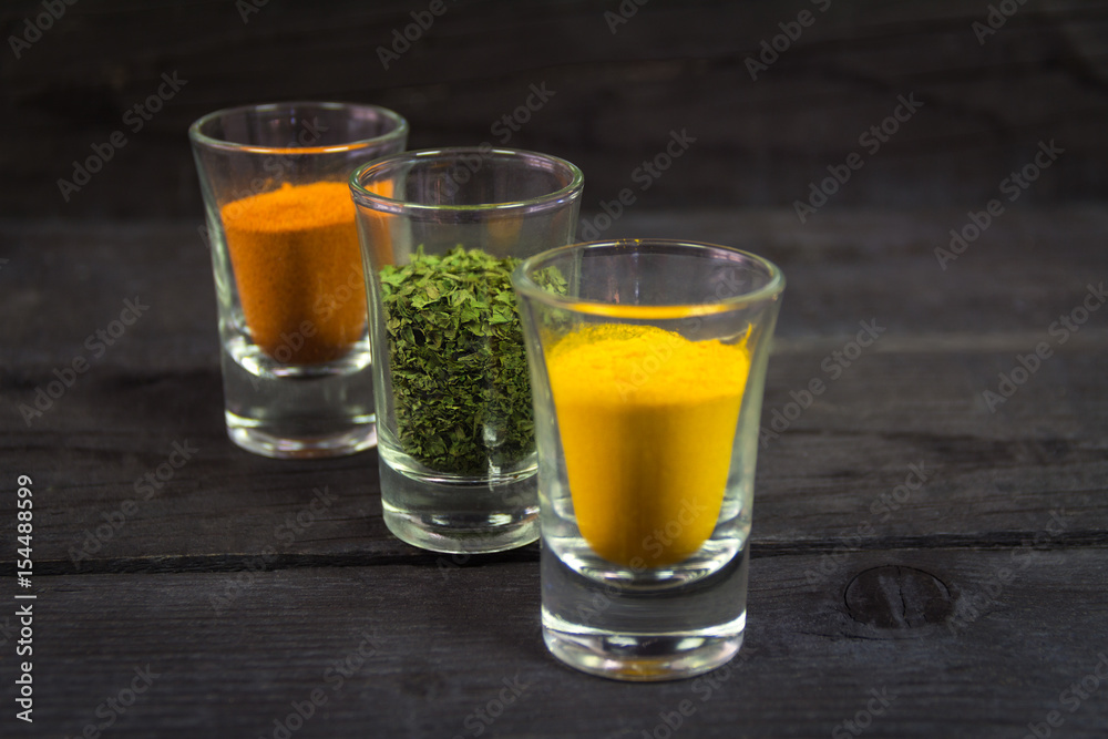 Spices in glasses on a wooden background
