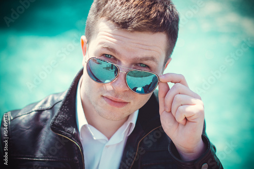 Lifestyle young man student in blue sunglasses walk around European streets