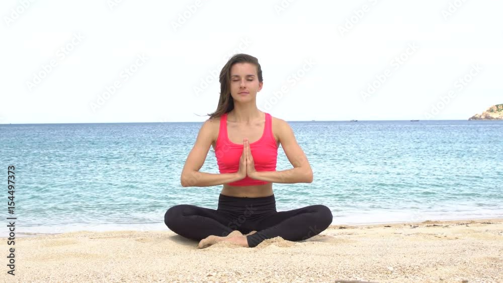 Young woman practicing yoga on the beach at sunset. Exercises calmness and harmony. Meditation in lotus pose. Healthy lifestyle. Young woman practicing yoga on the beach at sunset. Exercises calmness and harmony. Meditation in lotus pose. Healthy lifestyle.