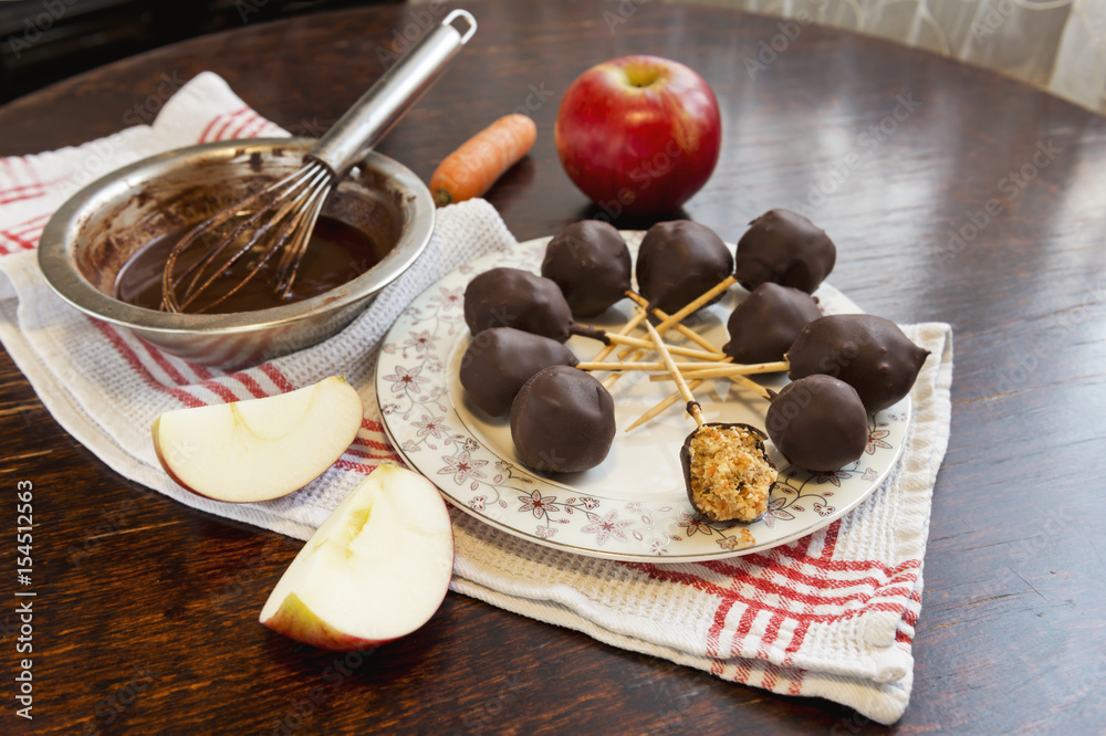 Healthy raw apple and carrot candies on sticks in raw chocolate