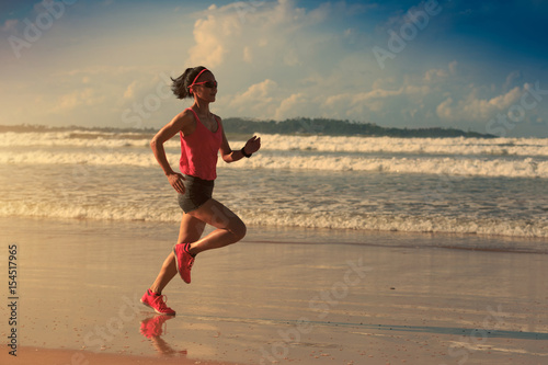 young fitness woman runner running on sunrise beach