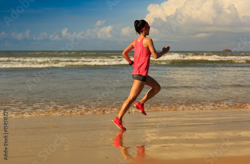 young fitness woman runner running on sunrise beach