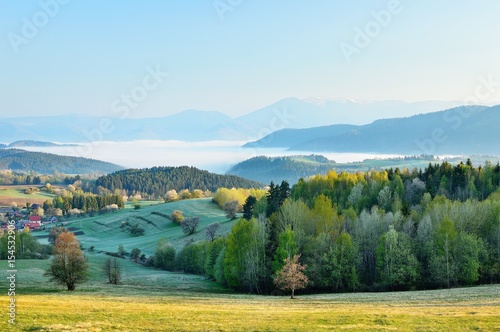 Spring meadows and fields landscape in Slovakia. Low Tatras panorama with snowy peaks. Blooming cherry trees. Cloudly inversion after the rain.