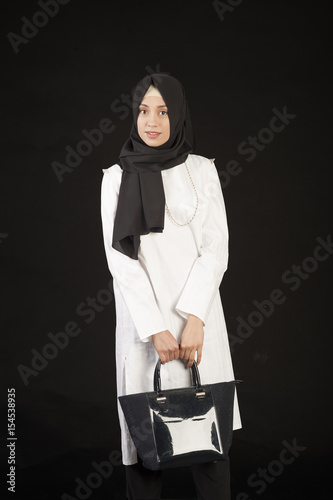 Beautiful Muslim woman in modern oriental clothes with handbag
