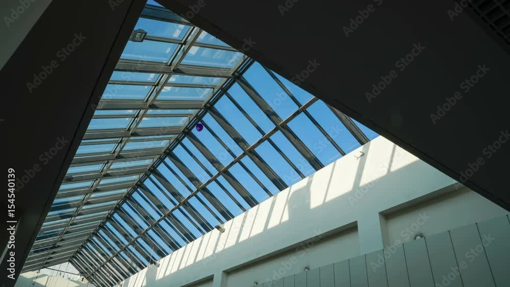 Glass ceiling of the shopping center with paper garlands on a background of time-lapse light of the sun rays on a blue sky