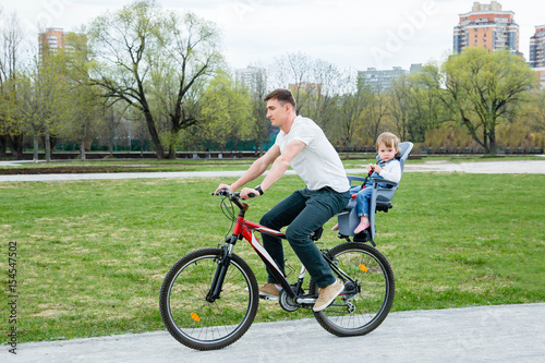 Young father and daughter riding a bicycle in the park