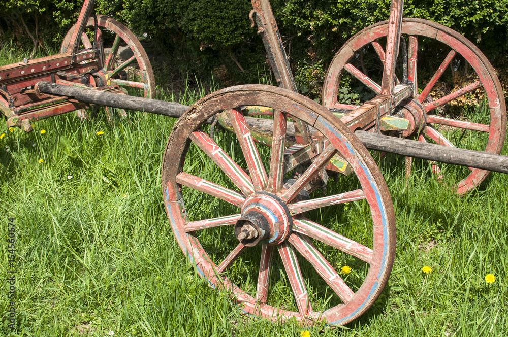 Wooden wheels on old rural cart on green grass meadow Wooden wheels on old rural cart on green grass meadow