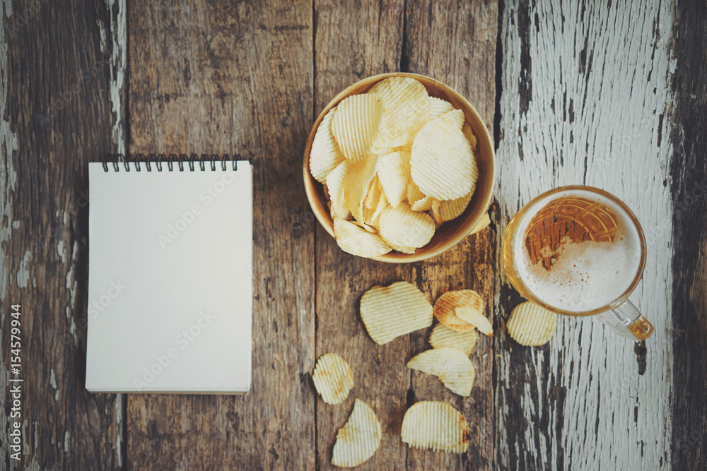 Lager beer, tomato chips and blank notebook on wooden table. Top view with copy space. Lager beer, tomato chips and blank notebook on wooden table. Top view with copy space.