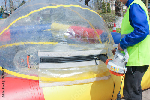 Man inflates a big balloon for the water rides. The injection of air in a huge balloon. Preparing for water attraction, the inflating ball pump large.