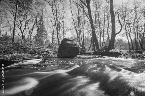 Waterfall in forest landscape long exposure flowing through trees and over rocks.