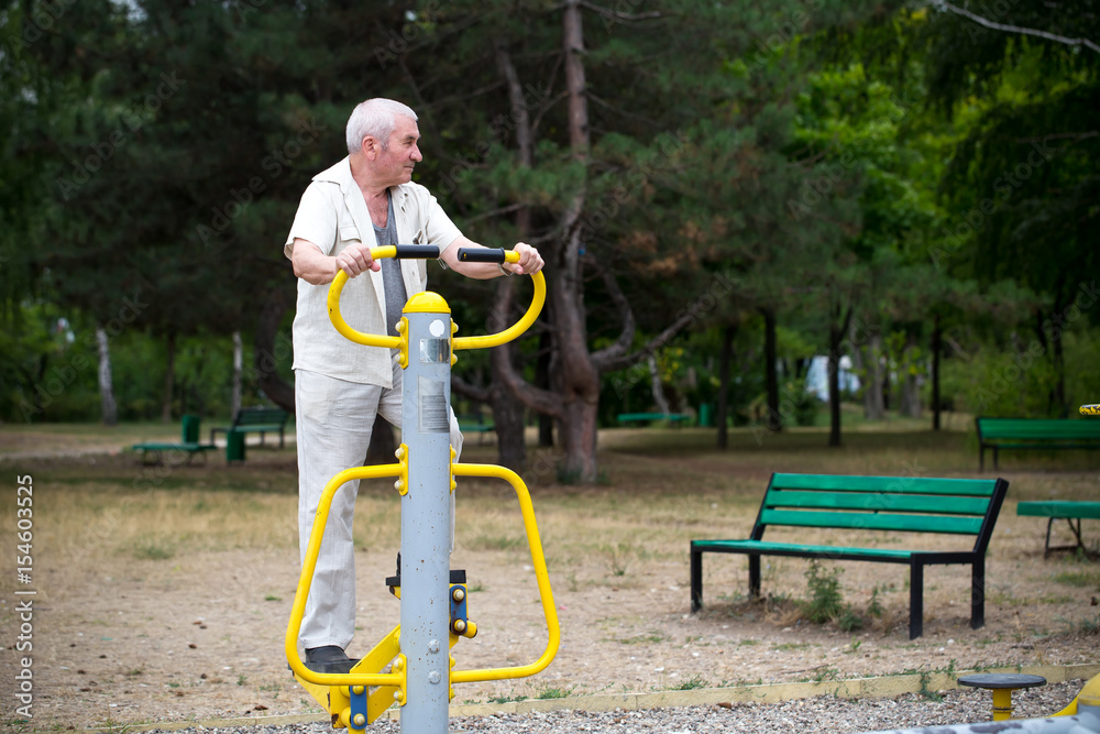 Fototapeta premium Old man making exercises on outdoor gym.