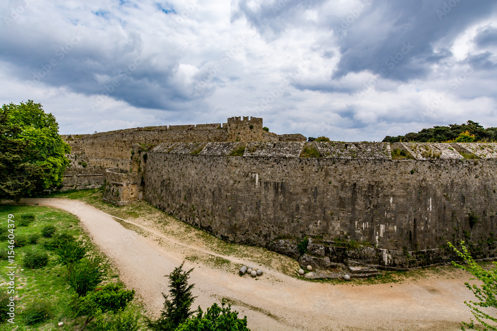 Medieval walls of Rhodes and moat under moody cloudy sky, Rhodes island, Greece Medieval walls of Rhodes and moat under moody cloudy sky, Rhodes island, Greece