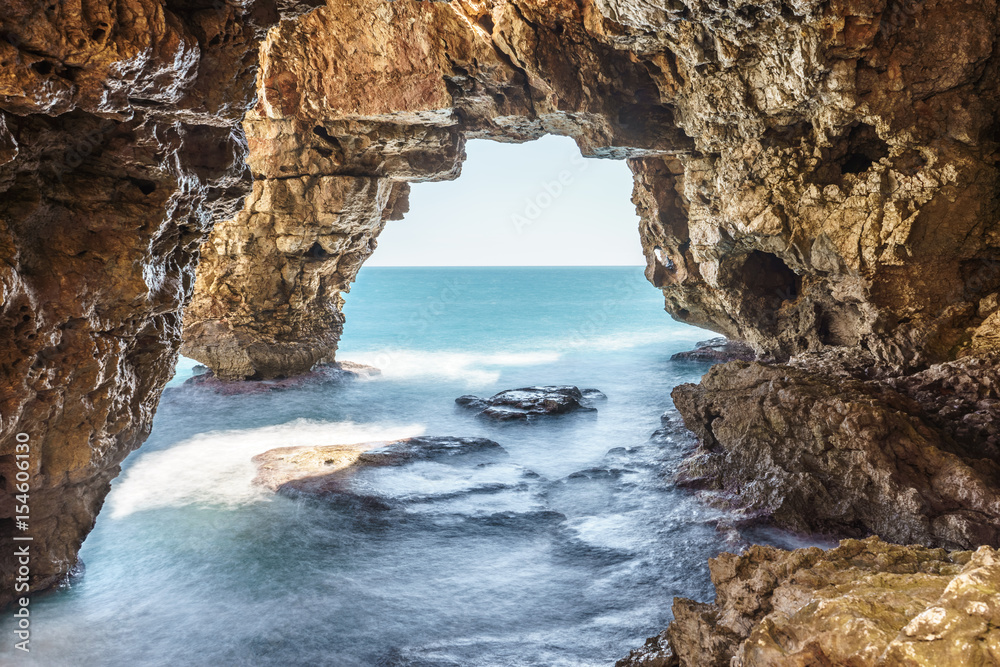 Long exposure image of caves of creek of Moraig, Benitatxell, Spain with mediterranean sea