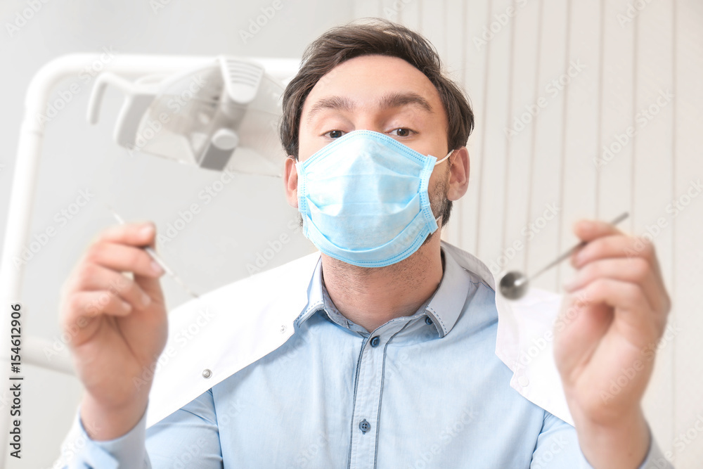 Dentist with mirror and periodontal explorer in clinic