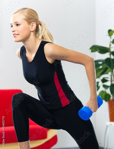 Woman exercising with dumbbell, at home
