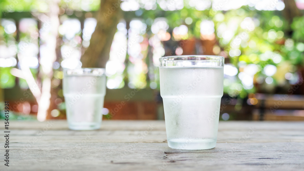 a glass of water on a wooden table. a glass of water on a wooden table.