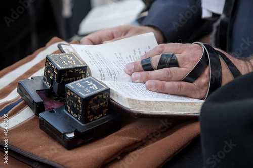 hands of a jew with tefilin are praying with a sidur - book of jewish traditional prayers at the Kotel, Jerusalem