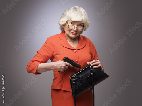 Old woman putting gun in handbag