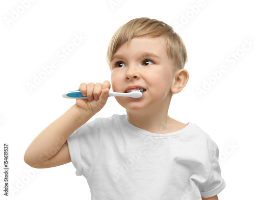 Cute little boy brushing teeth on white background