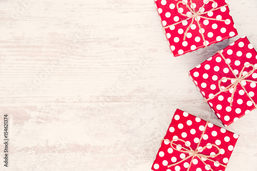 Red dotted gift boxes scattered over white wood background. Copy space.