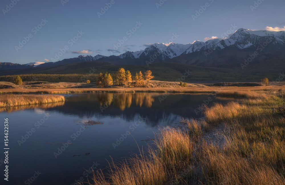 Mountain lake on a background of autumn landscape and snow capped mountains