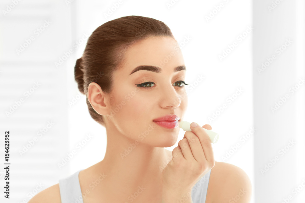 Beautiful young woman applying chapstick onto lips at home Beautiful young woman applying chapstick onto lips at home