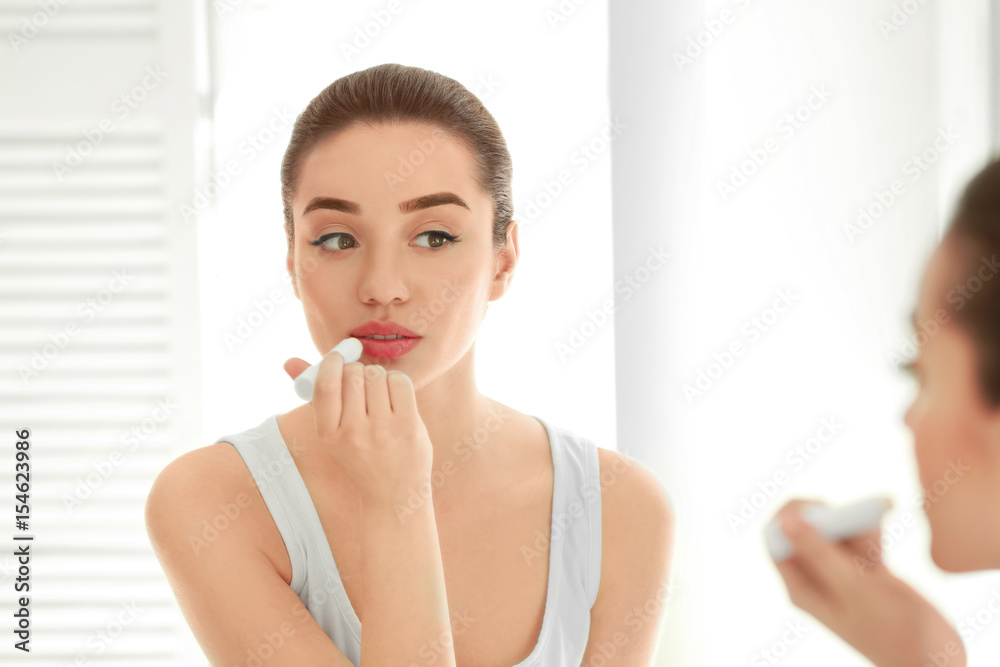 Beautiful young woman applying chapstick onto lips at home Beautiful young woman applying chapstick onto lips at home